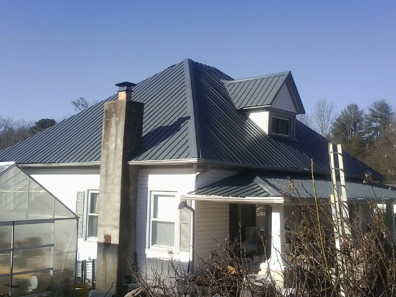 Dark blue standing seam metal roof on a white farmhouse with dormer — Slate & Tile Roof Repair by Roofing Brothers in West Hills