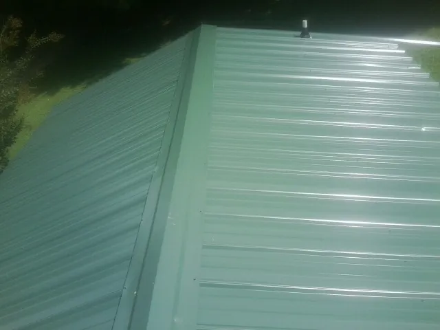 New green metal panels meeting at the ridge of a roof — Flat Roof Repair work by our crew in West Hills