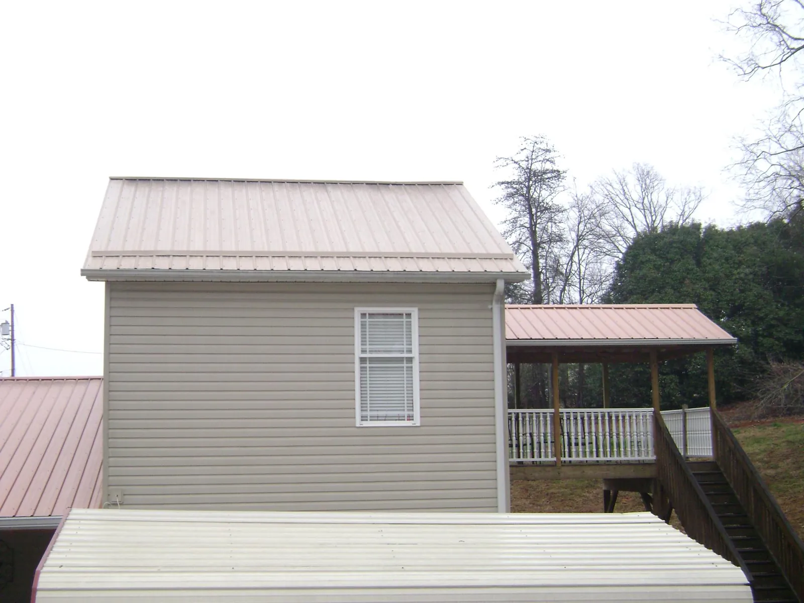 Tan metal roofs on a two story addition and attached porch, from a Roof Replacement job in West Hills