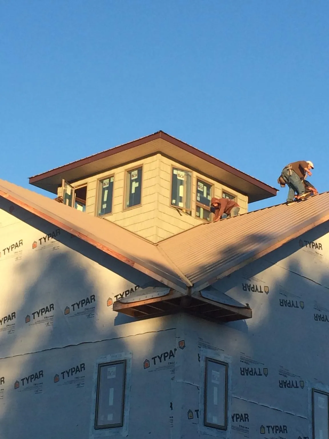 Roofers working around a rooftop cupola on a new metal roof at sunset — Roof Waterproofing in West Hills by Roofing Brothers